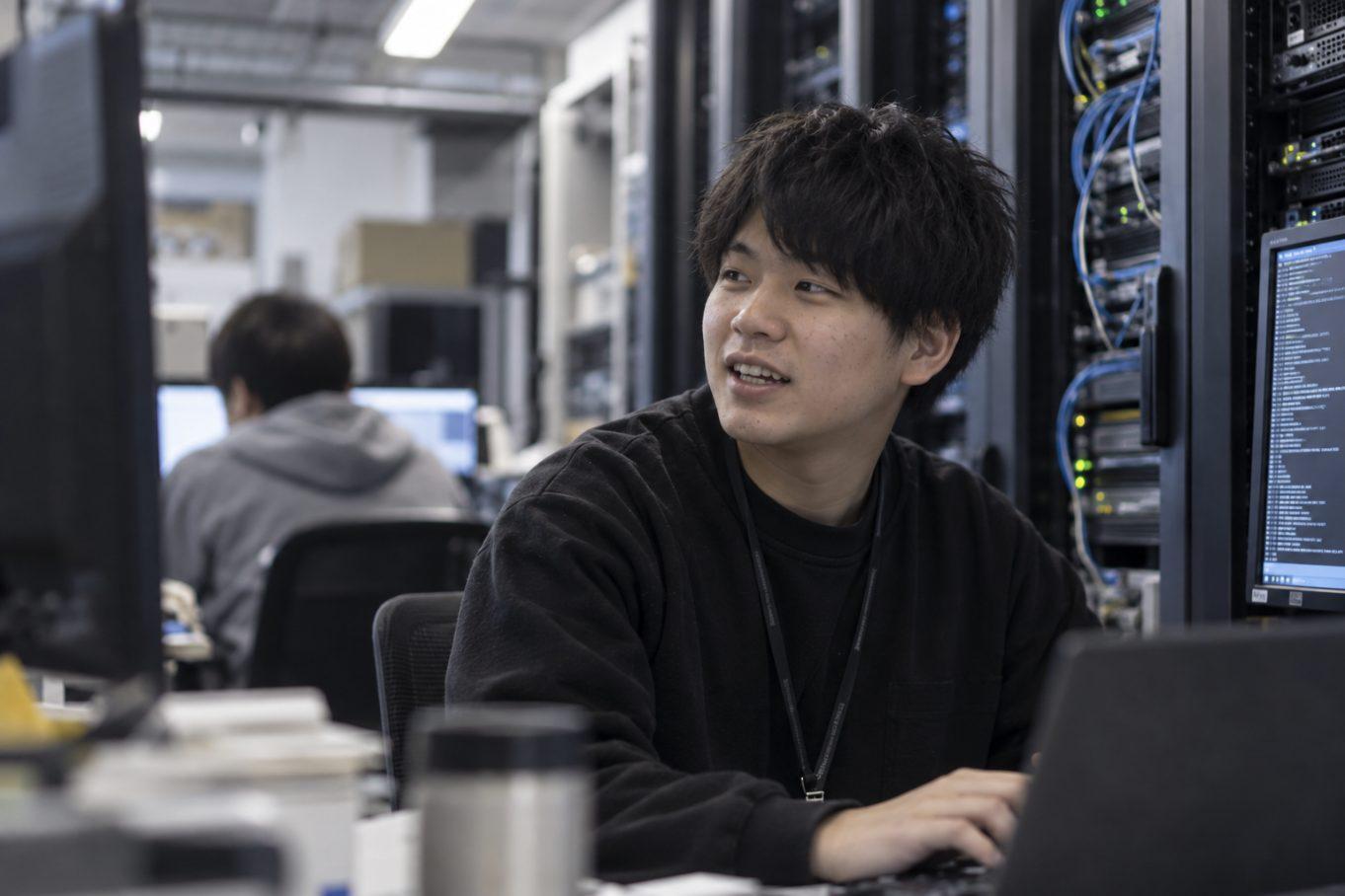 サーバールームでモニターに向かう若手エンジニア